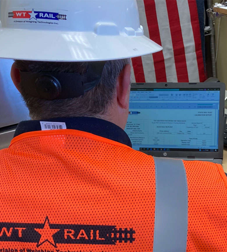 WT Rail Employee looking at computer screen showing a railroad scale calibration report. WT Rail performs rail scale calibrations with fully traceable equipment and provides customers with paperwork and calibration reports.